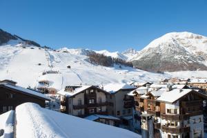 uma cidade coberta de neve com montanhas ao fundo em Hotel Crosal em Livigno