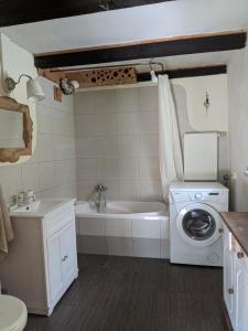a bathroom with a tub and a washing machine at Pokoje u Agnieszki in Dwernik