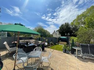 un patio con mesa, sillas y sombrilla en The Southbourne Villa, en Torquay