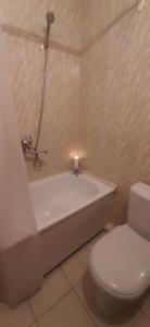 a bathroom with a toilet and a bath tub with a candle at Kandavas 2 in Daugavpils