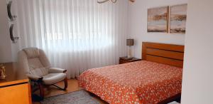 a bedroom with a bed and a chair next to a window at Vivenda Valverde in Nazaré