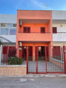 un edificio arancione con un cancello di fronte di Caravaggio Apartment a Porto Cesareo