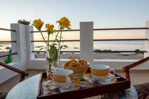 a table with two cups and a vase with bread at Tsampika's Beachfront House in Stegna in Archangelos