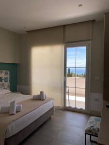um quarto com uma cama e uma grande porta de vidro deslizante em Drimades Blue Rooms em Dhërmi