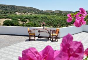 a table and chairs on a patio with pink flowers at Filio rooms in Kythira