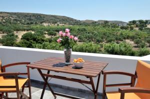 a wooden table with a vase of flowers on a balcony at Filio rooms in Kythira