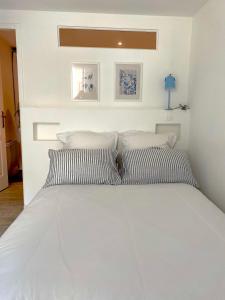 a bedroom with a white bed with two pillows at La petite maison bleue in Gruissan