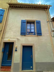 グリュイッサンにあるLa petite maison bleueの青いドア2つと窓2つが付いた建物