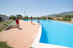 a group of people standing around a swimming pool at Cort'e Nastasj in Tertenìa