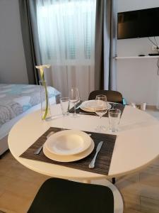 a white table with plates and wine glasses on it at Apartman Ružica in Pučišća