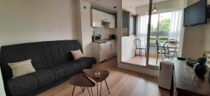 ein Wohnzimmer mit einem schwarzen Sofa und einer Küche in der Unterkunft LE LIBERTE - Studio cabine à 2 pas de la plage et du port in Saint-Cyprien