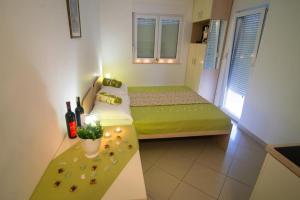 a small room with a green bed and a table at Apartmani Šantić in Baška Voda