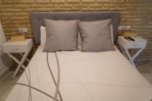 a bed with white sheets and pillows in a room at Balcón Giralda Center & Sweet in Seville