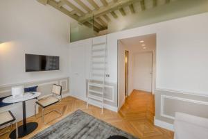 ein Wohnzimmer mit weißen Wänden sowie einem Tisch und Stühlen in der Unterkunft Appartement de standing 3 - tour Eiffel/Invalides in Paris