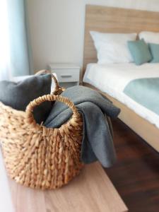 una cesta de mimbre sentada en el suelo junto a una cama en Bike & Spa Velence Apartman, en Velence