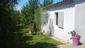 een wit huis met een raam en een tuin bij le gîte Lou Jas in Eyragues