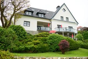a large white house with a black roof at Haus Aussicht - Ferienwohnungen Velden in Velden am Wörthersee