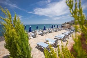 a row of lounge chairs and umbrellas on a beach at MOJO OTEL BEACH in Erdemli