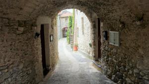 an alley with an archway in a stone building at La libellula rossa in Erli