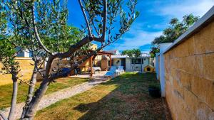 een boom in een tuin naast een huis bij Holiday home - Beach house 'Amarella' in Turanj