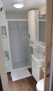 een witte badkamer met douche en wastafel bij SH Porto 1 Floating House, Marina Portorož in Portorož