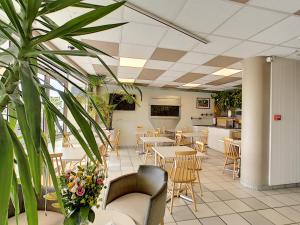 ein Restaurant mit Tischen, Stühlen und Pflanzen in der Unterkunft Logis Hôtel Rêve de Sable in Royan