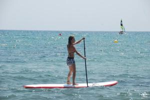 a woman standing on a paddle board in the ocean at Vila LYDIA in Cambrils