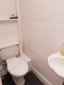 a white bathroom with a toilet and a sink at The Cardoun in Blackpool