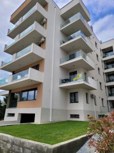 a white apartment building with a green lawn in front of it at Apartament Lux Eika in Mamaia Sat/Năvodari