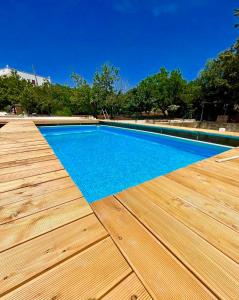 a swimming pool with a wooden deck and blue water at La casa di Colino e Annina in Monopoli