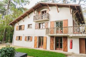 duży biały dom z drewnianymi drzwiami i oknami w obiekcie Roofless Surf Lodge w mieście Soorts-Hossegor