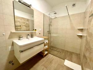 La salle de bains blanche est pourvue d'un lavabo et d'une douche. dans l'établissement Ida 3 Apartments, à Dubrovnik