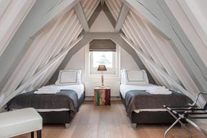 two beds in a attic room with a window at Residences Canal Area in Amsterdam