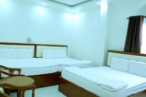 een kamer met drie bedden en een tafel en een stoel bij HOTEL ĐĂNG KHOA 2 NÚI SAM in Chau Doc