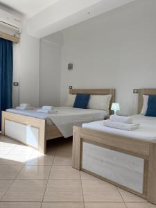 two beds sitting in a room with blue curtains at Villa White in Ksamil