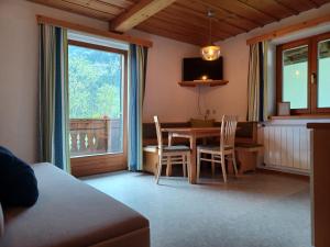 a living room with a table and chairs and a window at Ferienwohnungen Asterbach in Gosau