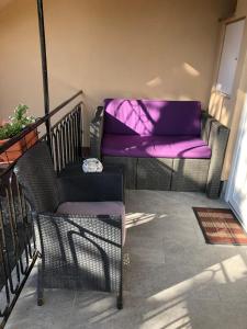 balkon z krzesłem i kanapą z fioletowymi poduszkami w obiekcie Apartman-Tata w mieście Tata