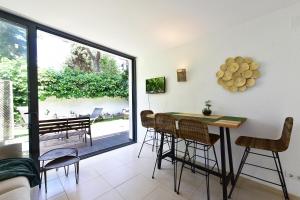 カダケスにあるApartamento con jardincito en el centro de CADAQUÉSのテーブルと椅子と窓のあるダイニングルーム
