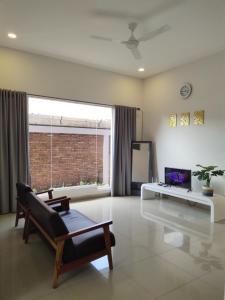 a living room with a large window and a chair at Tropical Cozy House in the heart of Medan in Medan