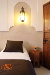 a bedroom with a bed and a lamp and a table at Riad CHERRATA in Marrakesh