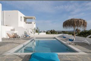 a swimming pool with chairs and an umbrella and a house at Villa Ester Naxos in Kastraki