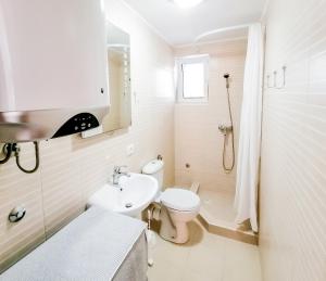 a white bathroom with a toilet and a sink at Apartments Siesta in Tivat