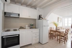 een keuken met witte apparatuur en een tafel met stoelen bij Alessios Houses Mykonos Town in Mykonos-stad