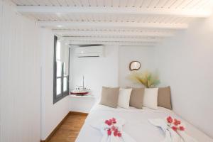 ein weißes Schlafzimmer mit einem Bett mit roten Blumen darauf in der Unterkunft Alessios Houses Mykonos Town in Mykonos Stadt