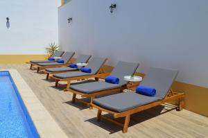 a row of chaise lounge chairs next to a pool at Cuba Real in Cuba