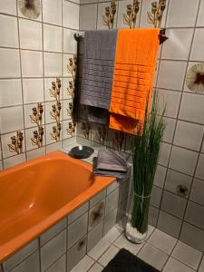 Apartment Ananas I Zentral & SeeNah في بويرشاك آم فورثيرسي: حوض استحمام برتقالي في الحمام مع المناشف