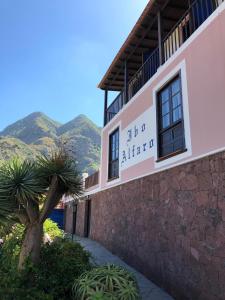 a building with a sign on it with mountains in the background at Hotel Rural Ibo Alfaro - OFFLINE HOTEL in Hermigua