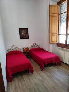Cette chambre comprend 2 lits avec des couvertures rouges et une fenêtre. dans l'établissement Accanto al Duomo, à Florence