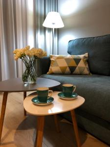 a living room with two coffee tables with cups and flowers at Apartament Kameleon in Dźwirzyno