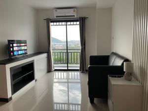 a living room with a couch and a television and a window at Siri Residence Bowin in Ban Phan Sadet Nai